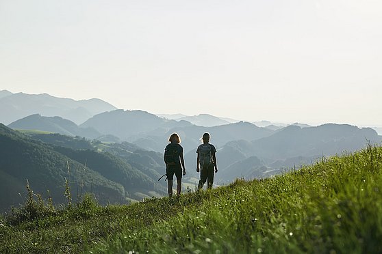 Foto Oberösterreich Tourismus GmbH/Stefan Mayerhofer: Zwei junge Frauen wandern auf einer Wiese, im Hintergrund das Ennstal